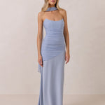 Woman wearing a light blue strapless gown with ruching against a plain background