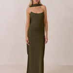 Woman wearing an olive green halter neck dress with ruching throughout the bodice against a plain background