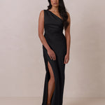 Woman wearing a black evening gown with a slit on a plain background