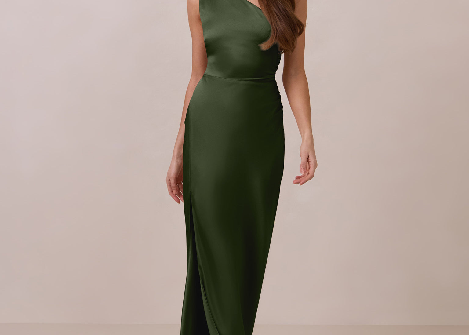 Woman wearing a green one-shoulder dress against a beige background