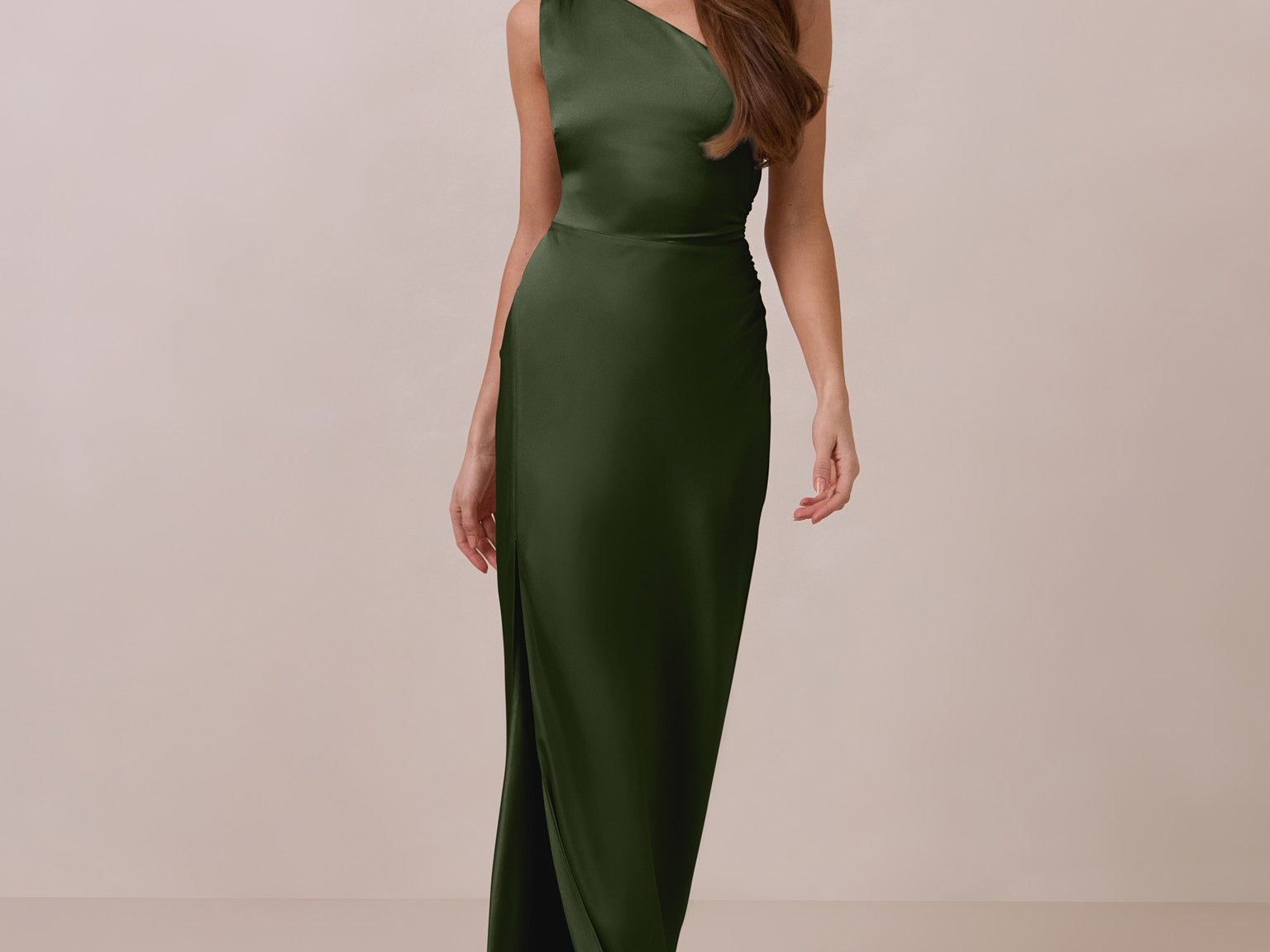Woman wearing a green one-shoulder dress against a beige background