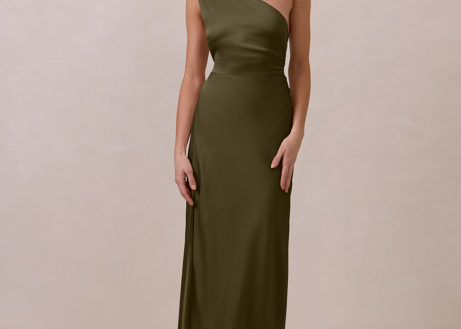 Woman wearing a green one-shoulder dress against a beige background
