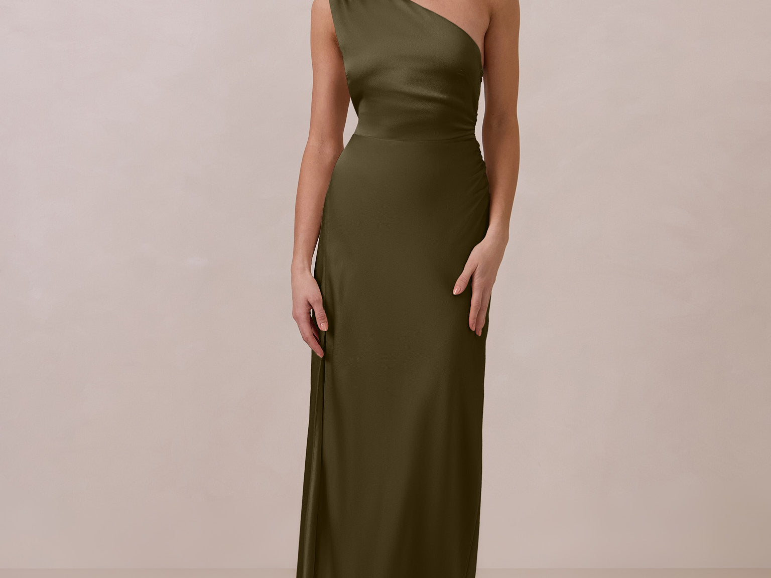 Woman wearing a green one-shoulder dress against a beige background