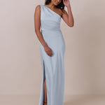 Woman wearing a light blue one-shoulder gown with a slit on a beige background