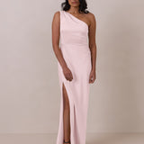 Woman wearing a one-shoulder pink gown with a slit on a plain background