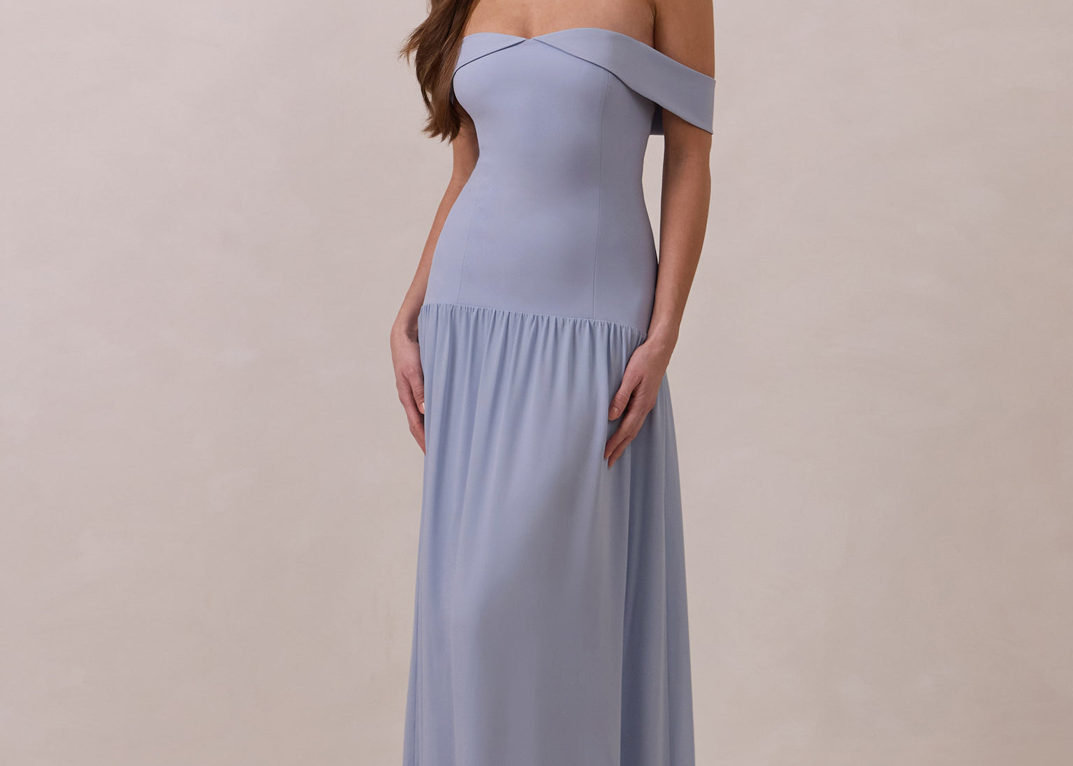 Woman wearing a light blue off-shoulder gown against a beige background