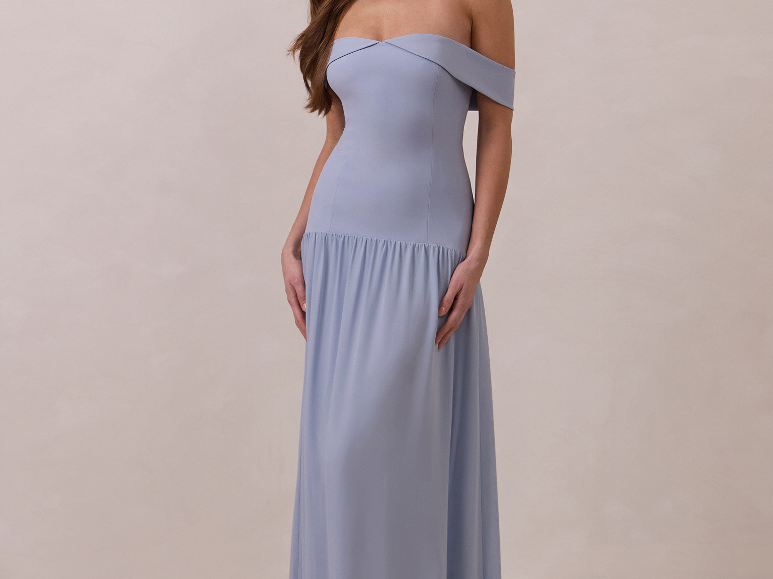 Woman wearing a light blue off-shoulder gown against a beige background