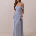 Woman wearing a light blue off-shoulder gown against a beige background