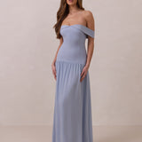 Woman wearing a light blue off-shoulder gown against a beige background