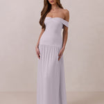 Woman wearing a light purple off-shoulder chiffon gown against a plain background