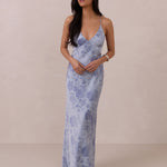 Woman wearing a blue floral dress against a beige background