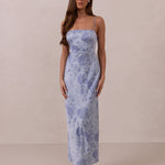 Woman wearing a thin strap floral dress against a plain background