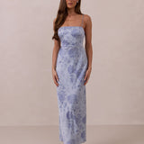 Woman wearing a thin strap floral dress against a plain background