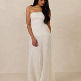 Woman wearing a white strapless gown against a beige background