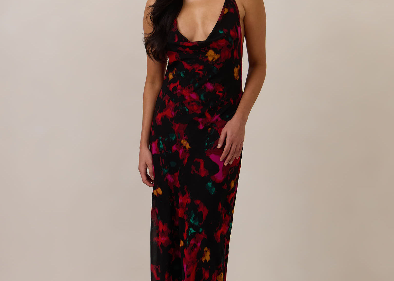 Woman wearing a black, red, orange and teal patterned dress against a plain background