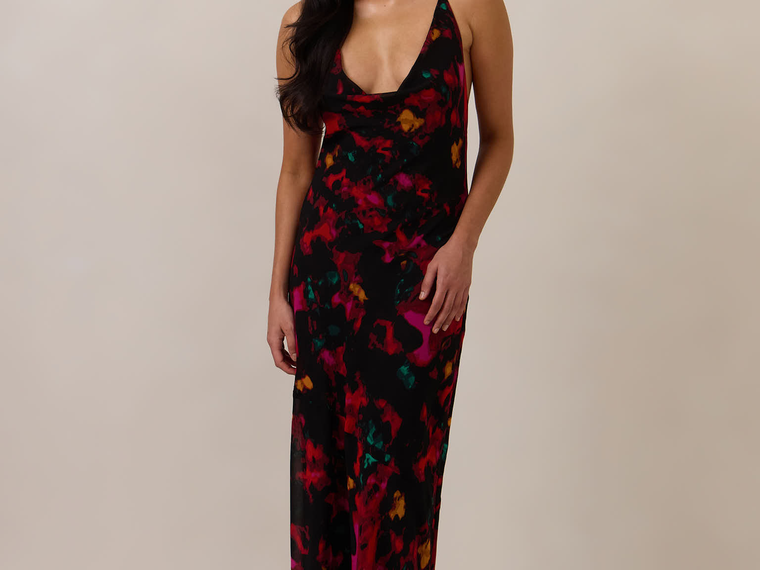 Woman wearing a black, red, orange and teal patterned dress against a plain background