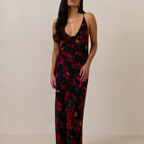 Woman wearing a black, red, orange and teal patterned dress against a plain background