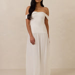 Woman wearing a white off-shoulder dress against a plain background