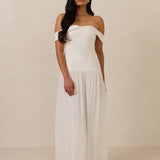 Woman wearing a white off-shoulder dress against a plain background