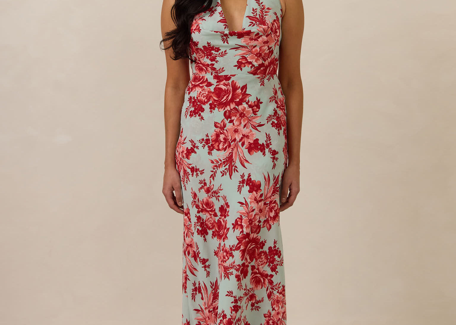 Woman wearing a teal and red floral dress against a beige background