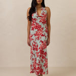 Woman wearing a teal and red floral dress against a beige background