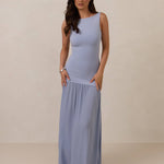 Woman wearing a blue dropped waist dress against a plain background