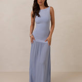 Woman wearing a blue dropped waist dress against a plain background