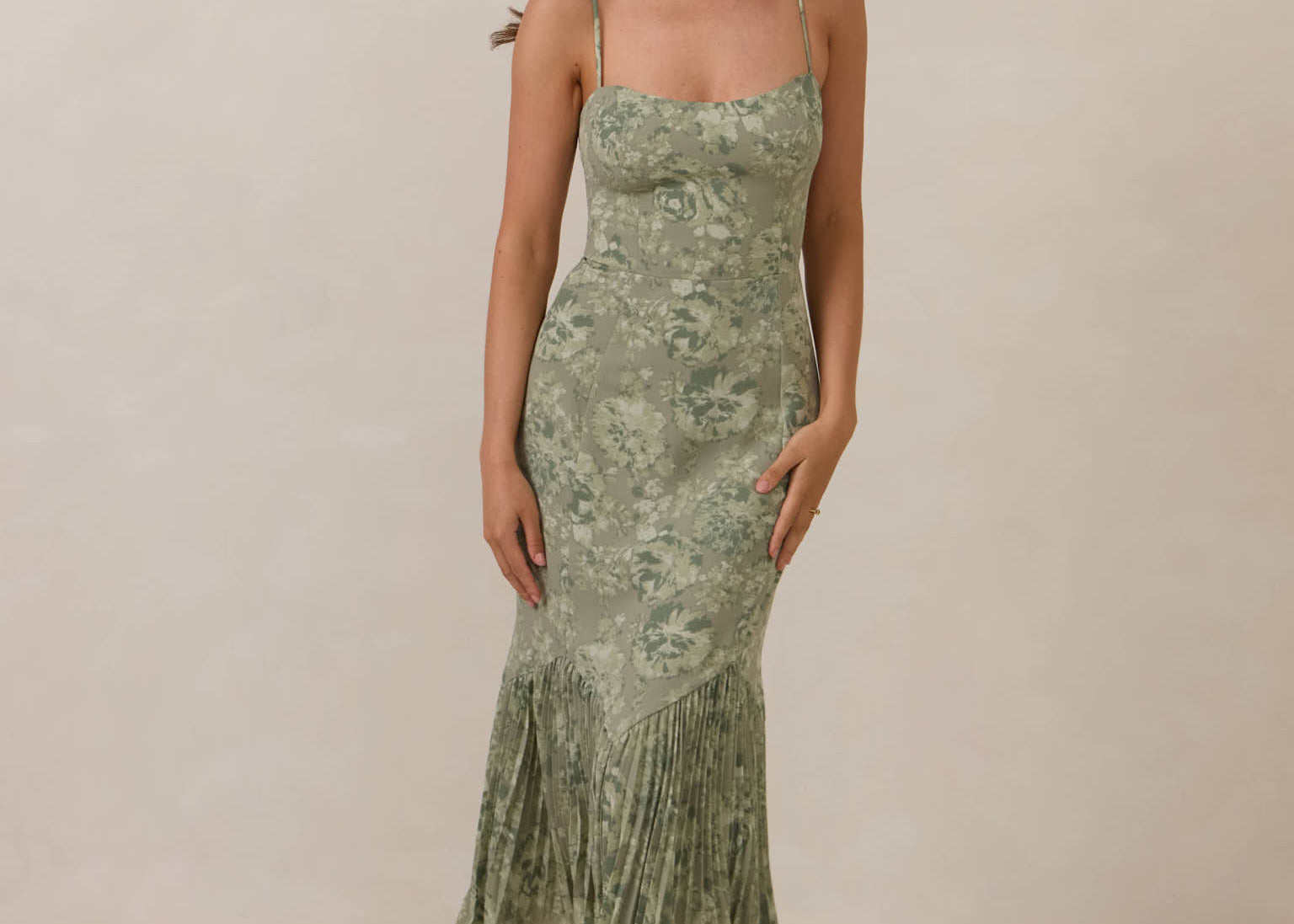 Woman wearing a green floral dress against a plain background