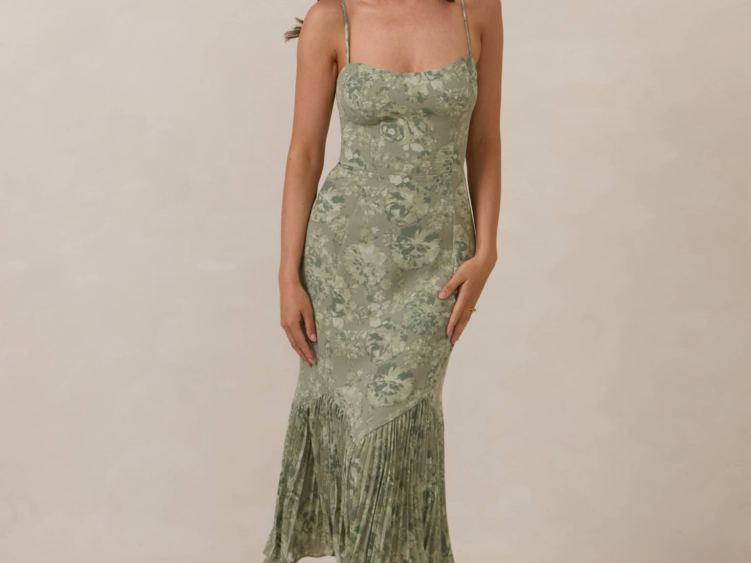 Woman wearing a green floral dress against a plain background