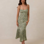 Woman wearing a green floral dress against a plain background