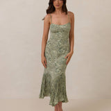 Woman wearing a green floral dress against a plain background